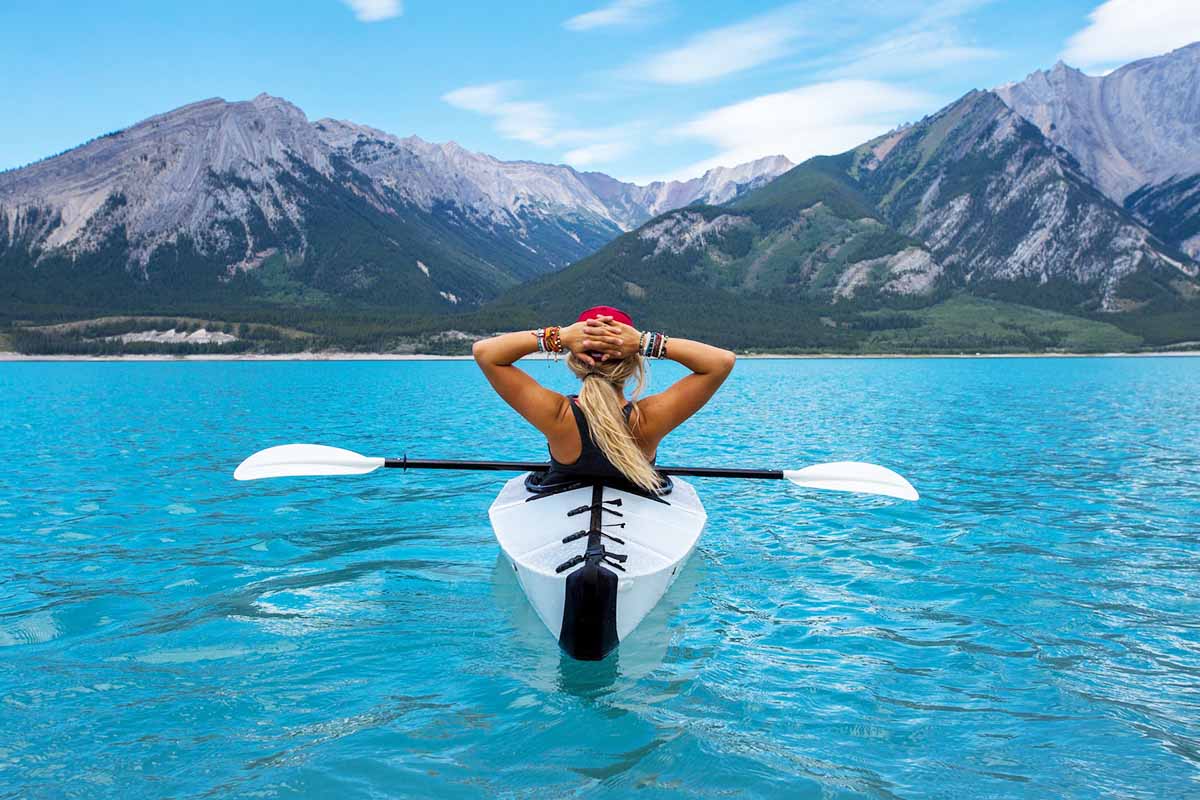 A person in a kayak, looking at some mountains